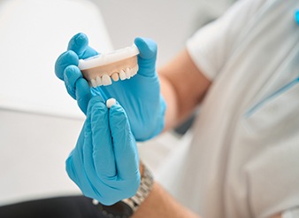A dentist holding a model of a dental crown