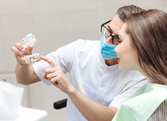 Dentist showing patient dental implant model