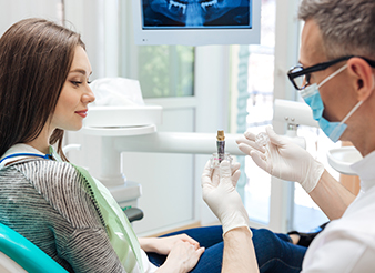 Dentist and patient looking at dental implant model