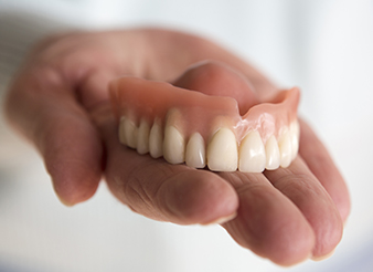 Hand holding a full denture