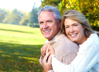 An older couple smiling outside.