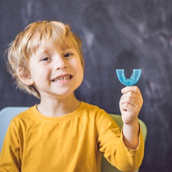 Child holding a blue orthodontic appliance