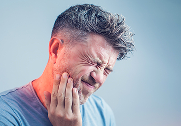 Man holding cheek in pain