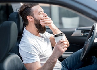 A man yawning in his car.
