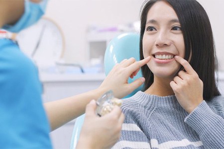 Woman smiling while dentist points at her teeth.