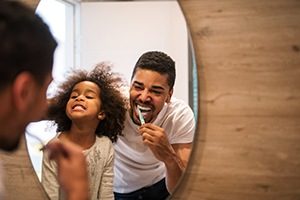 Father and daughter brushing teeth