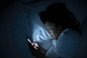 Woman lying in bed looking at her cell phone