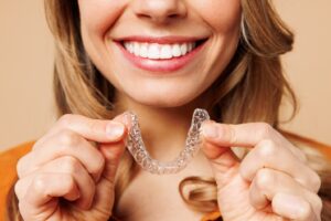 Woman with pretty smile holding clear aligner.